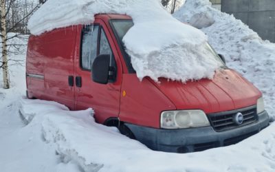 punainen pakettiauto lumen peittämänä