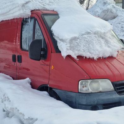 punainen pakettiauto lumen peittämänä
